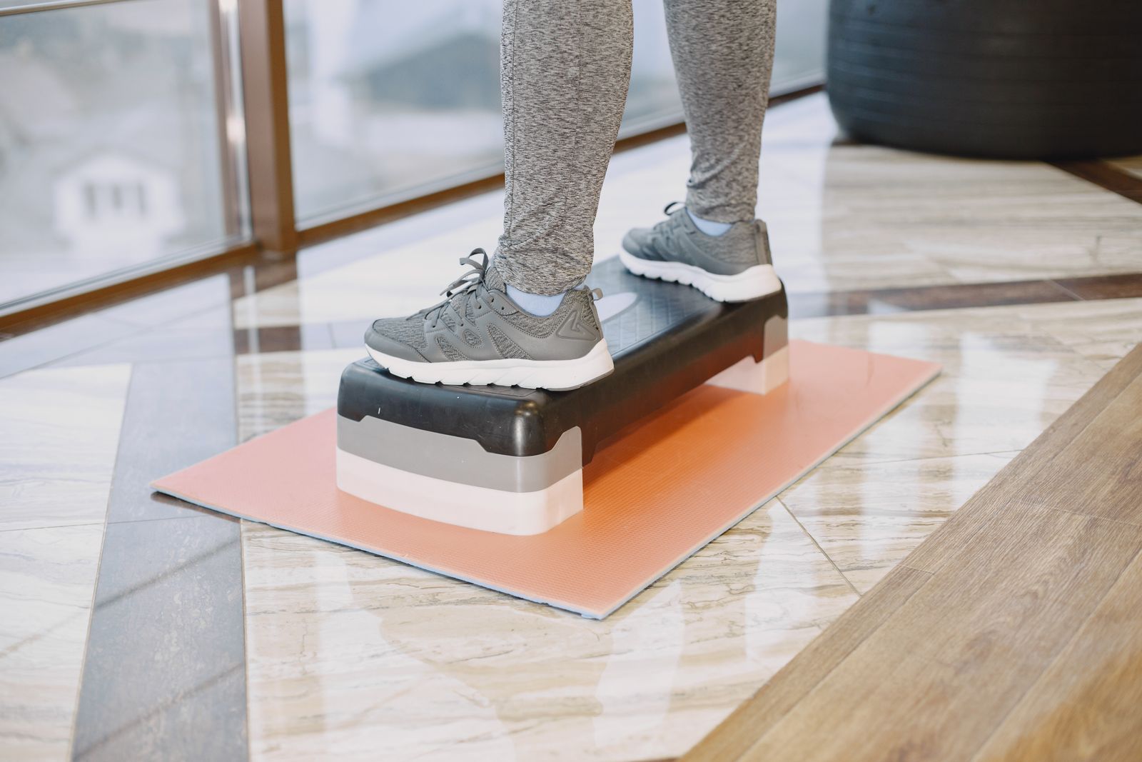 Person in sneakers standing on an exercise step, the kind of setup used for calf raises that support shockwave therapy for Achilles tendinitis in Hinsdale, IL