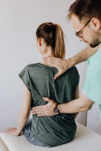 Clinician examining a patient's lower back during hands-on treatment for low back pain, like the care offered at Adisi Health Center in Hinsdale, IL.