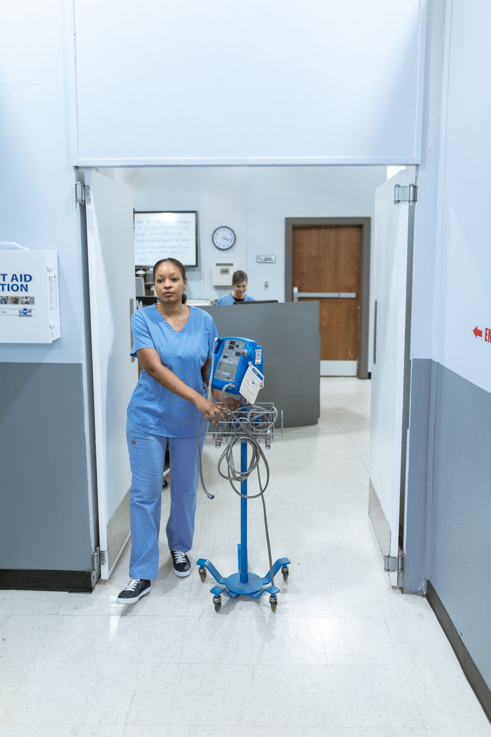 Nurse in blue scrubs walking a hospital hallway, the kind of on-your-feet job that can lead to plantar fasciitis heel pain treated in Hinsdale, IL