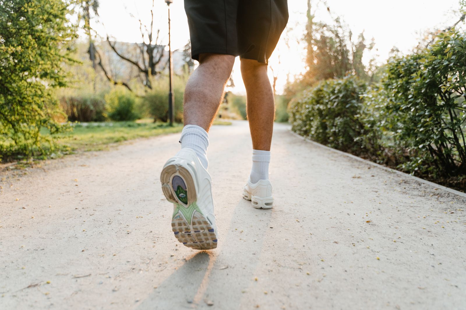 Runner in white sneakers jogging on a sunny park path, active and pain-free after plantar fasciitis treatment in Hinsdale
